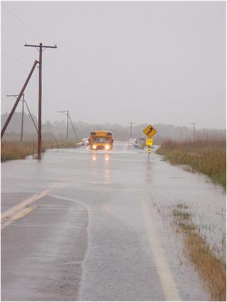 A school bus  tries to cross a flooded road