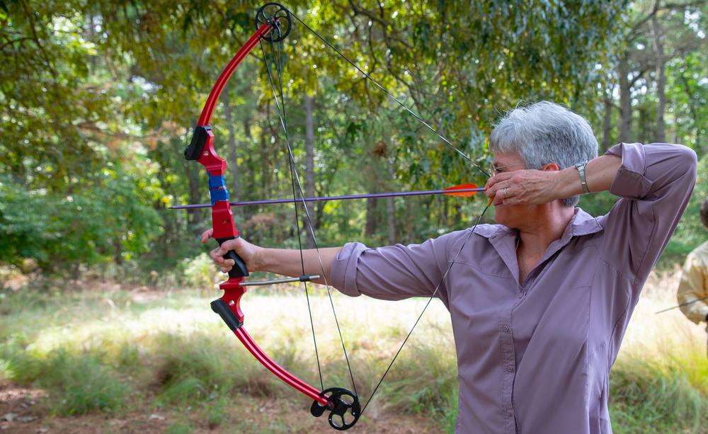 A woman draws back an arrow preparing to fire it with a compound bow. 