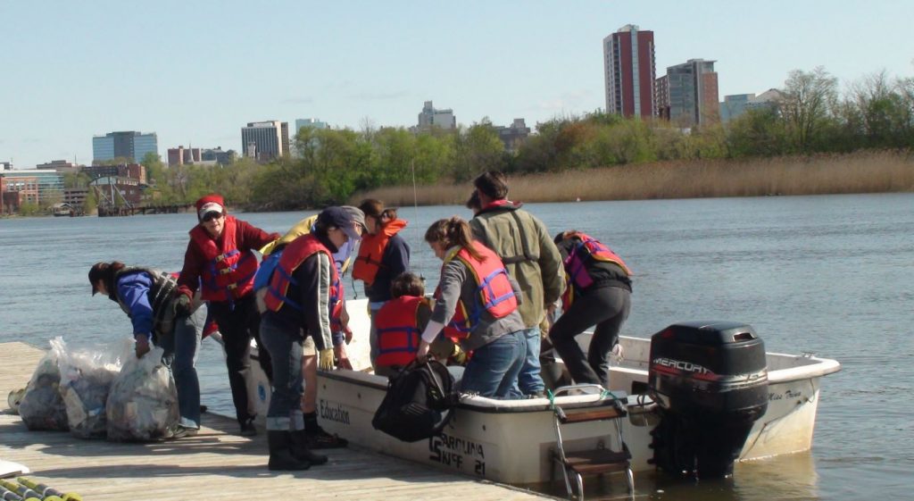 volunteers unload trash from a boat on a river