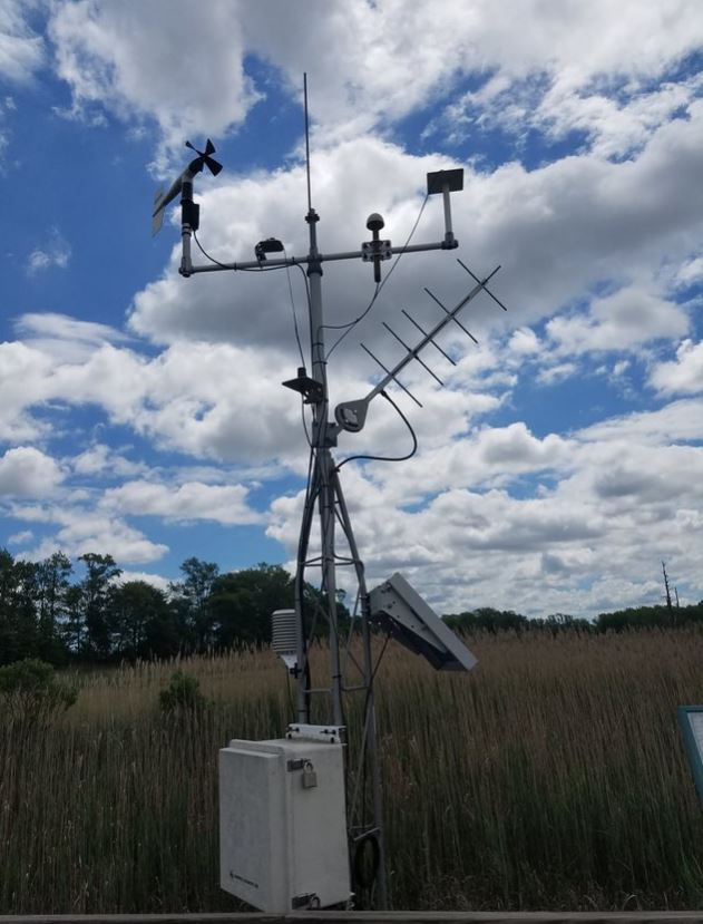 A collection of weather-re;ated instruments are mounted near a marsh