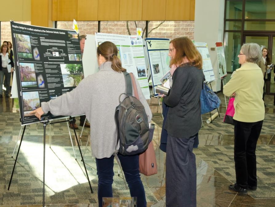 Conference attendees study student posters