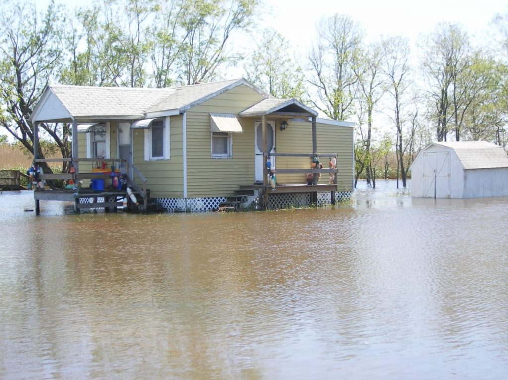 A small house sits completely surrounded by flood waters.