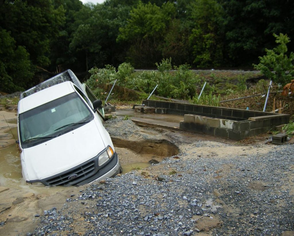 A white truck is partially buried in mud left from a flood event.