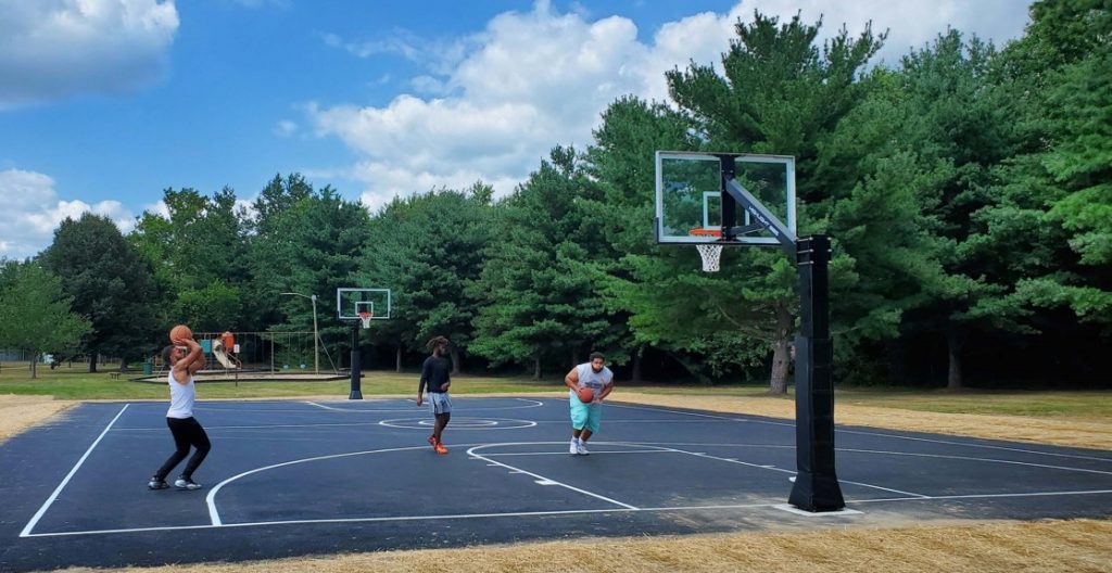Three young people playing basketball on a newly-built court.