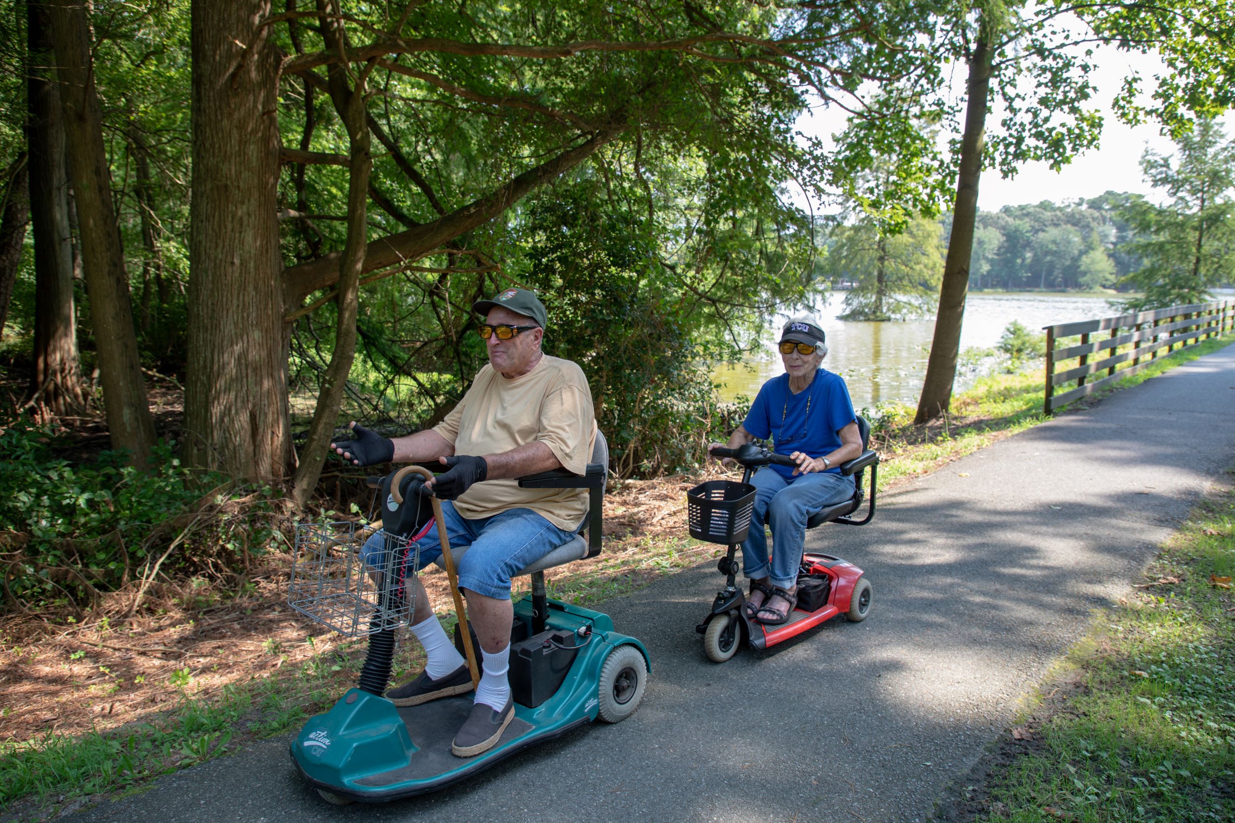 A couple on a trail at Trap Pond State Park using personal mobility scooters.