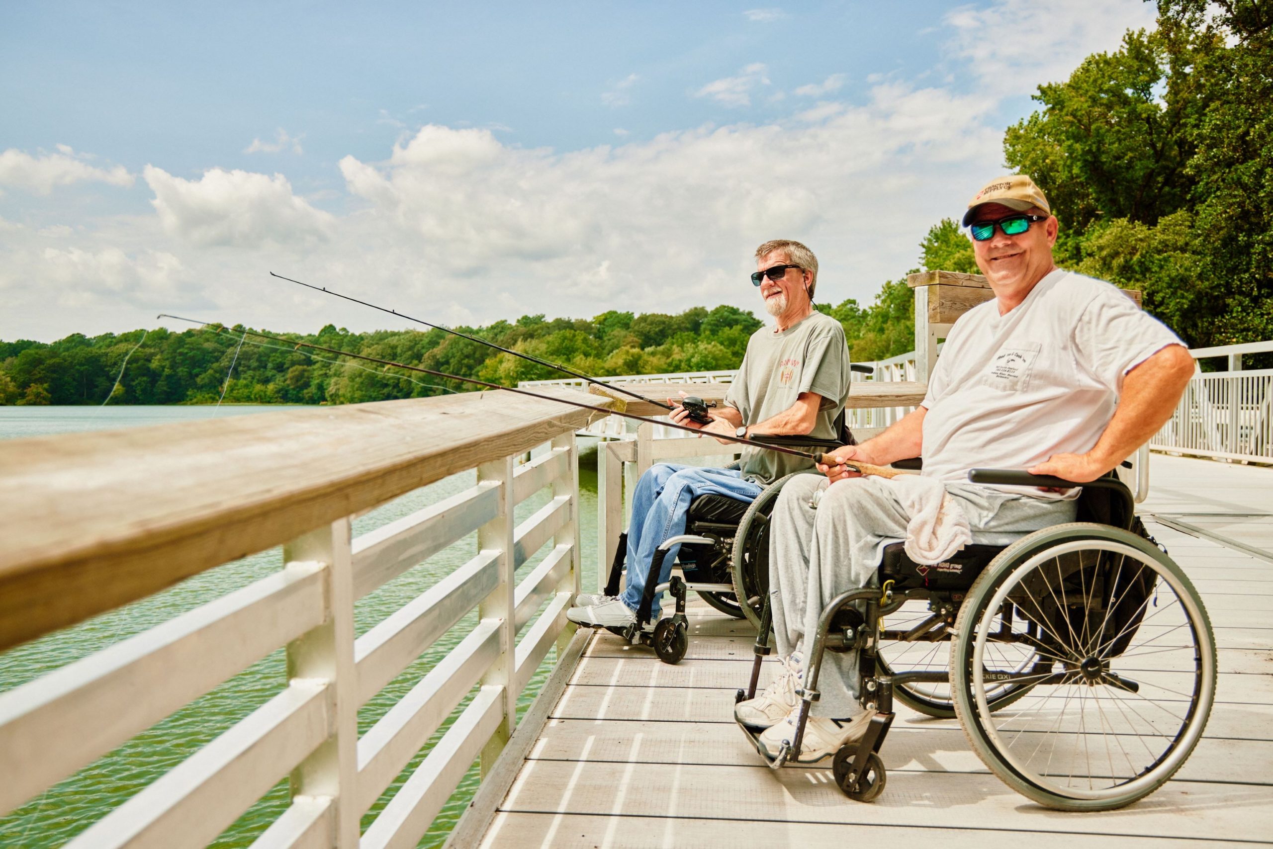 Two men in wheelchairs fish from an accessible deck.