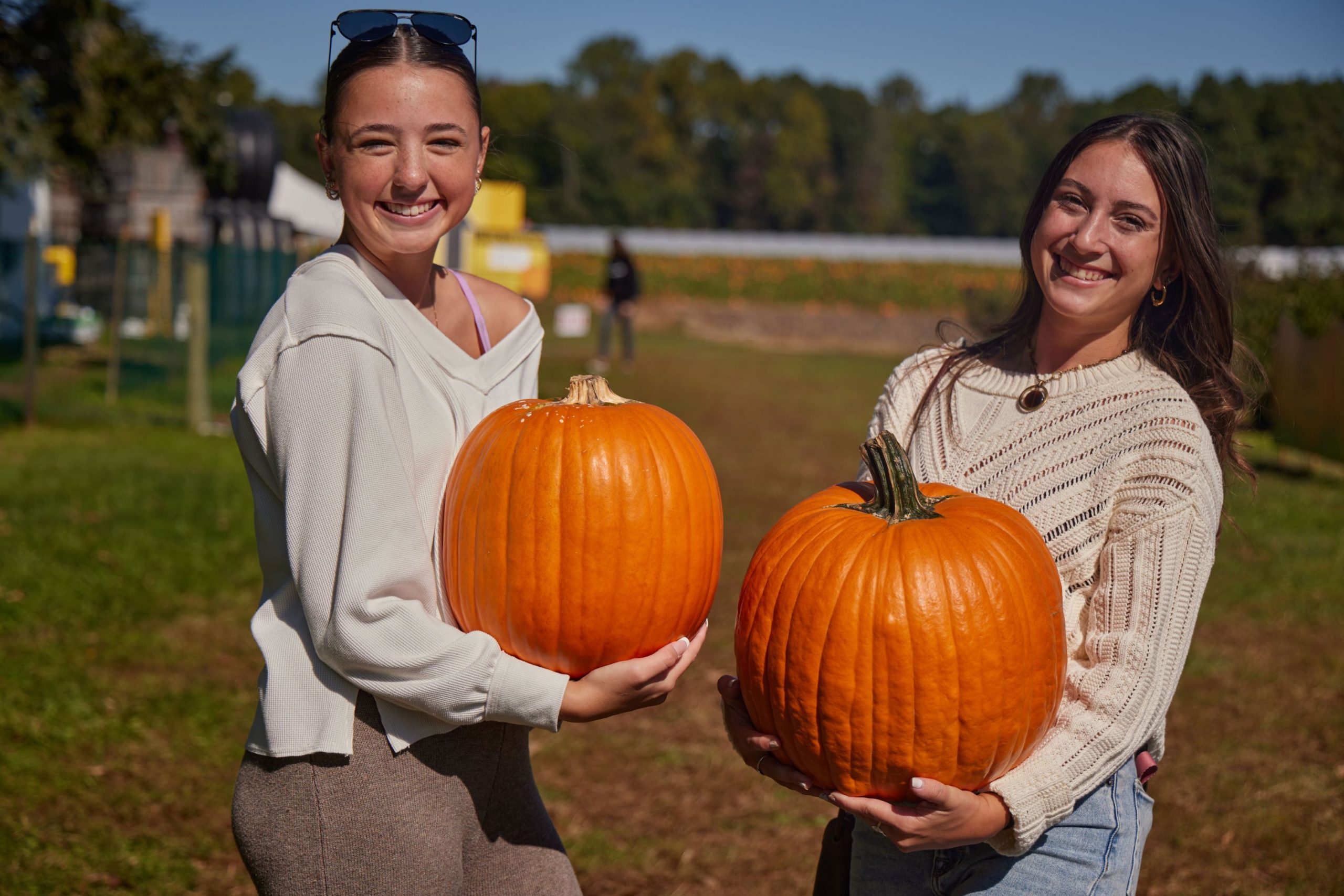 Two girls, each holding a large pumpkin at Fifer's Orchard.