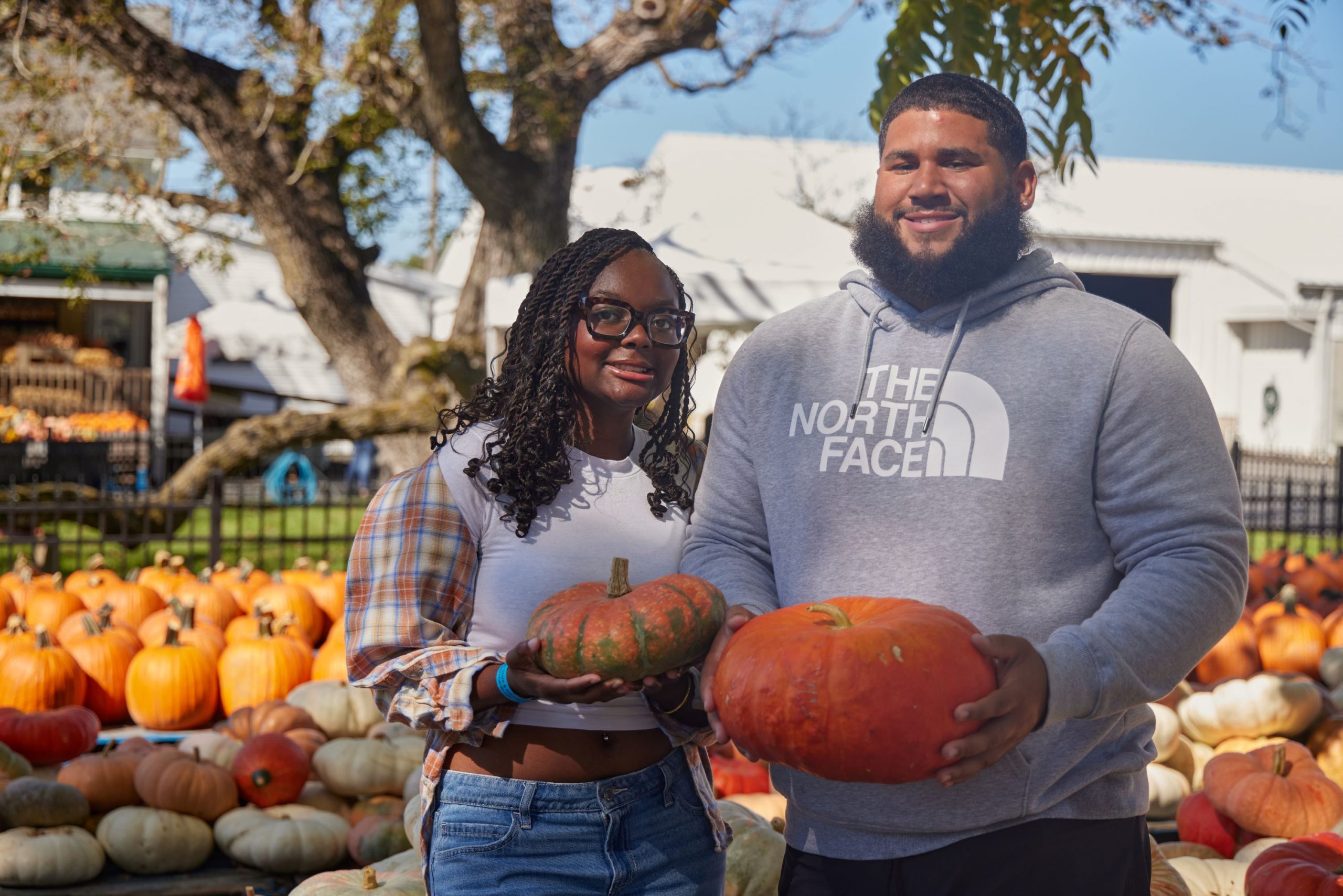 Two people show off the pumpkins they bought from Fifer Orchards.