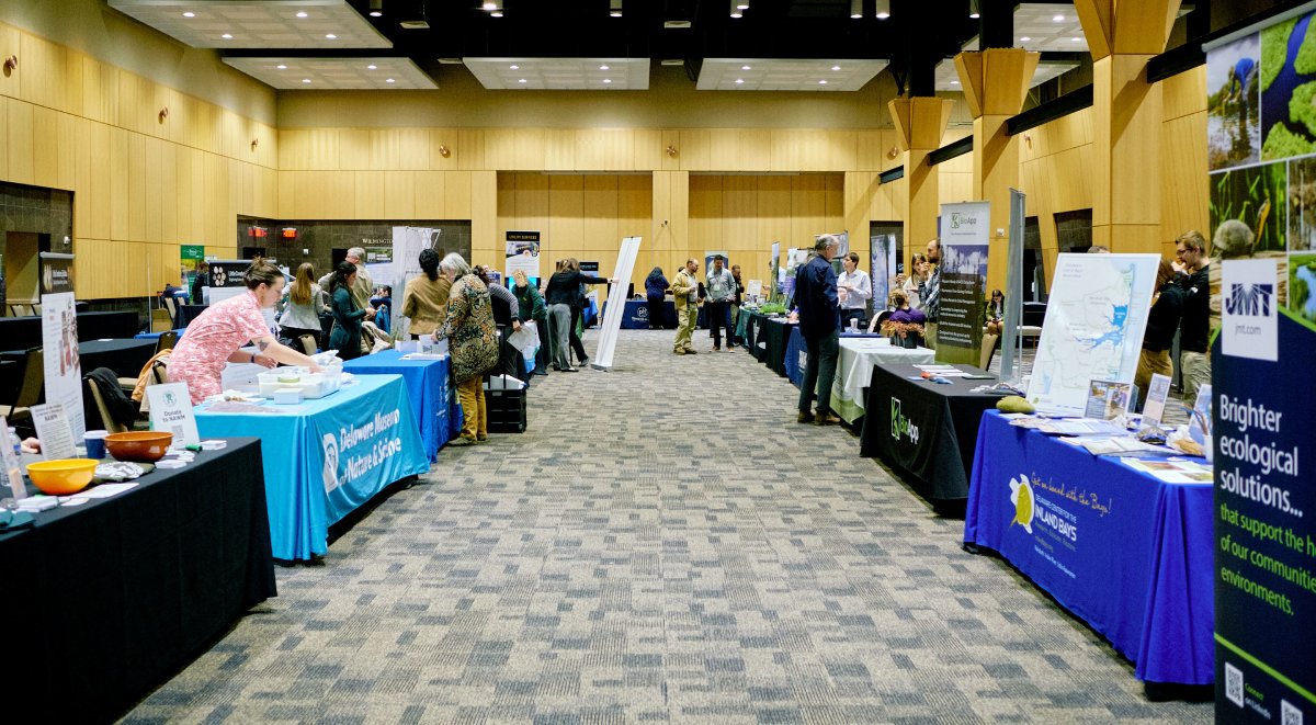 A room filled with exhibitor tables at a conference.