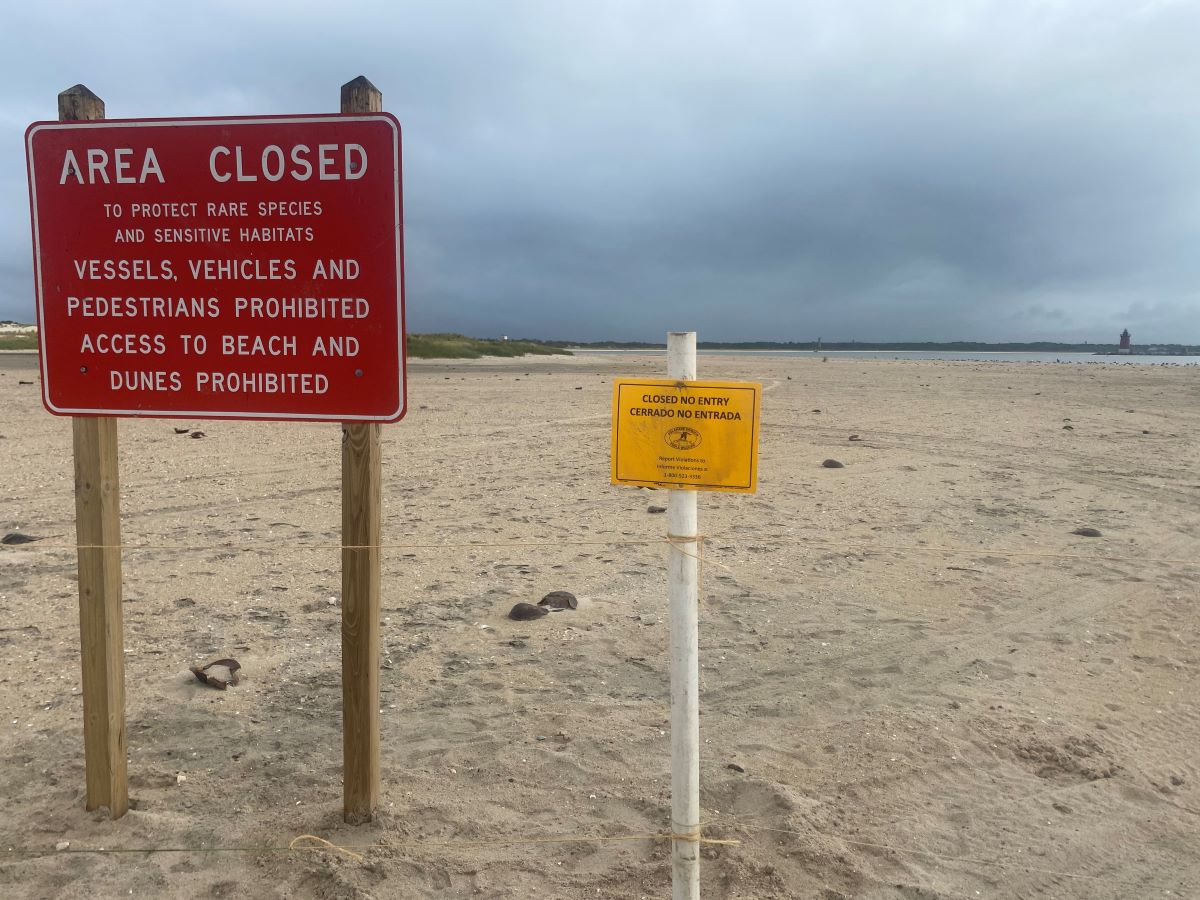 A large red sign reads: Area Close, to protect rare species and sensitive habitats. Vessels vehicles and pedestrians prohibited. Access to beach and dunes prohibited.