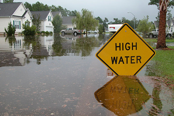 Flood waters rise up to a sign warning people of high water in a residential neighborhood.