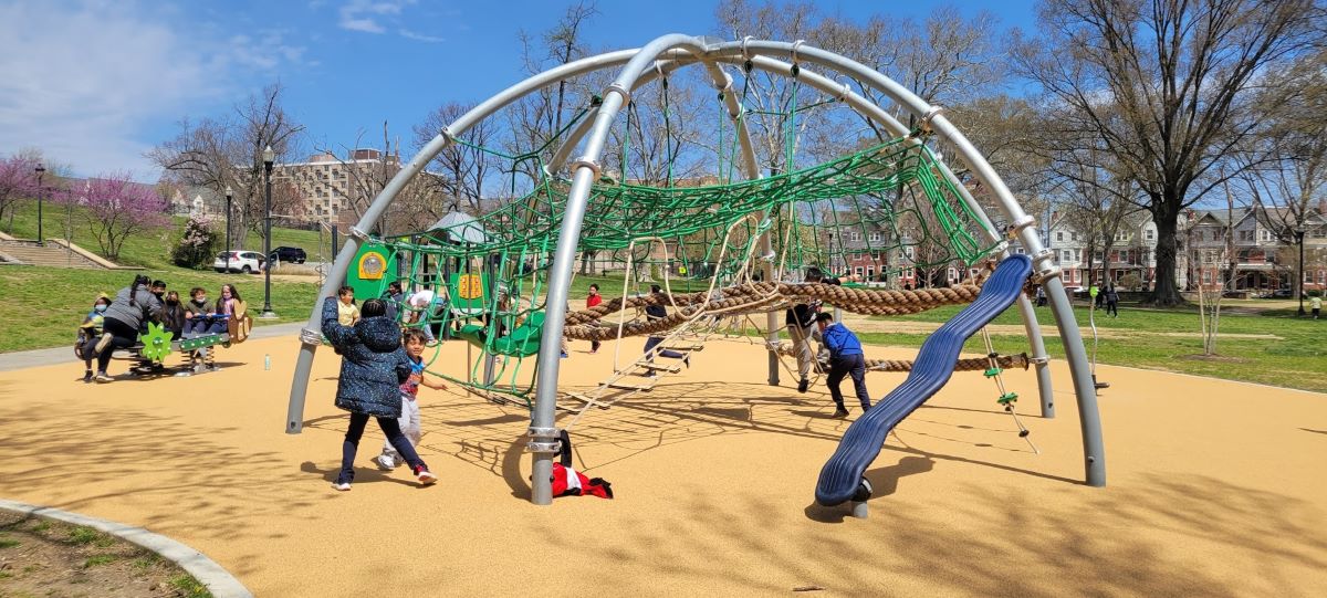 A group of children play on new playground equipment.