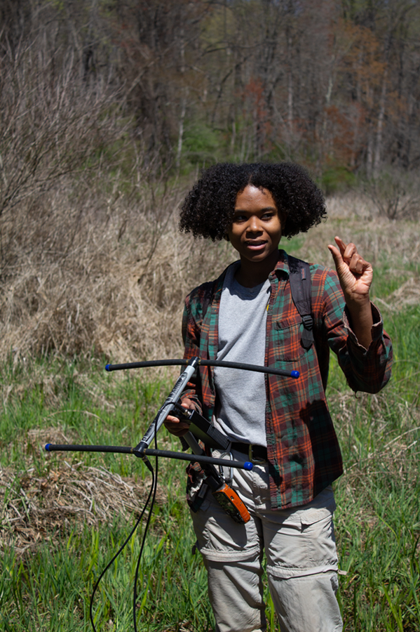 A woman holds an antenna-like radio transmitter.