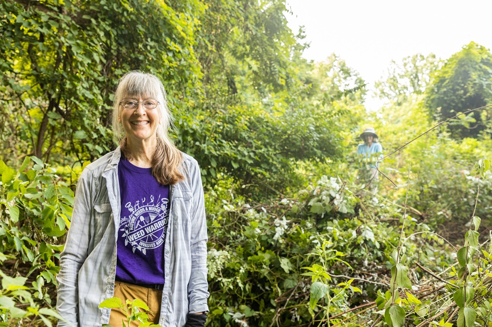 A woman smiles in front of trees.