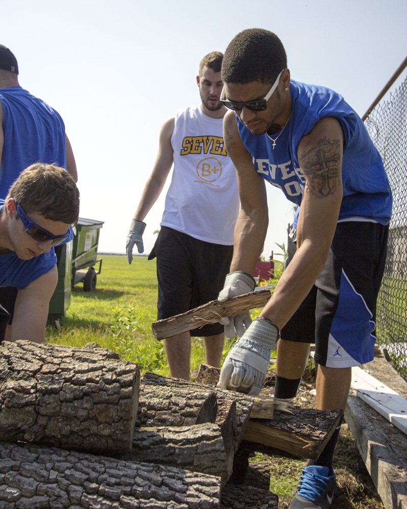Several men stack wood.