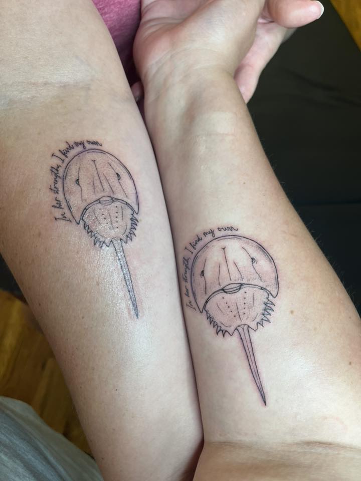 Two people show horseshoe crab tattoos on their forearms.