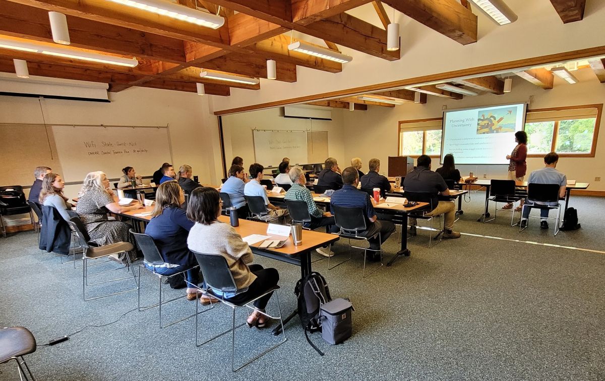 Attendees at a workshop listen to a speaker using a screen to share a presentation.