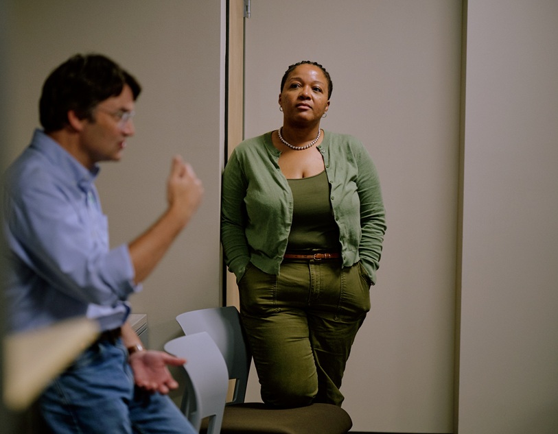 A woman listens as a man speaks in the foreground.