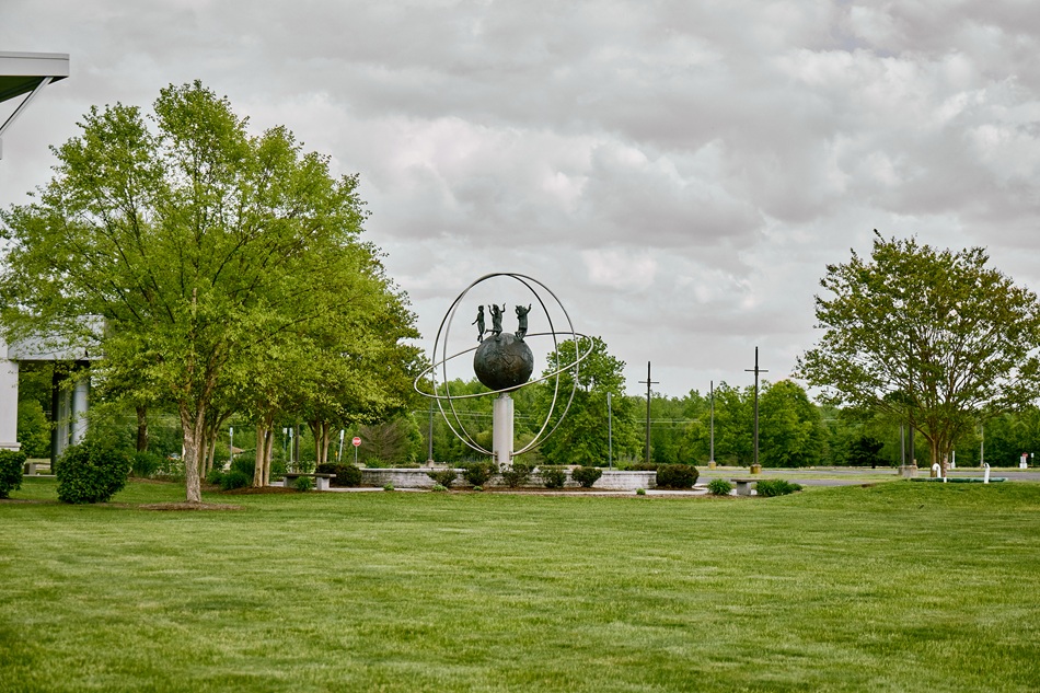 A metal sculpture shows children standing on the Earth.