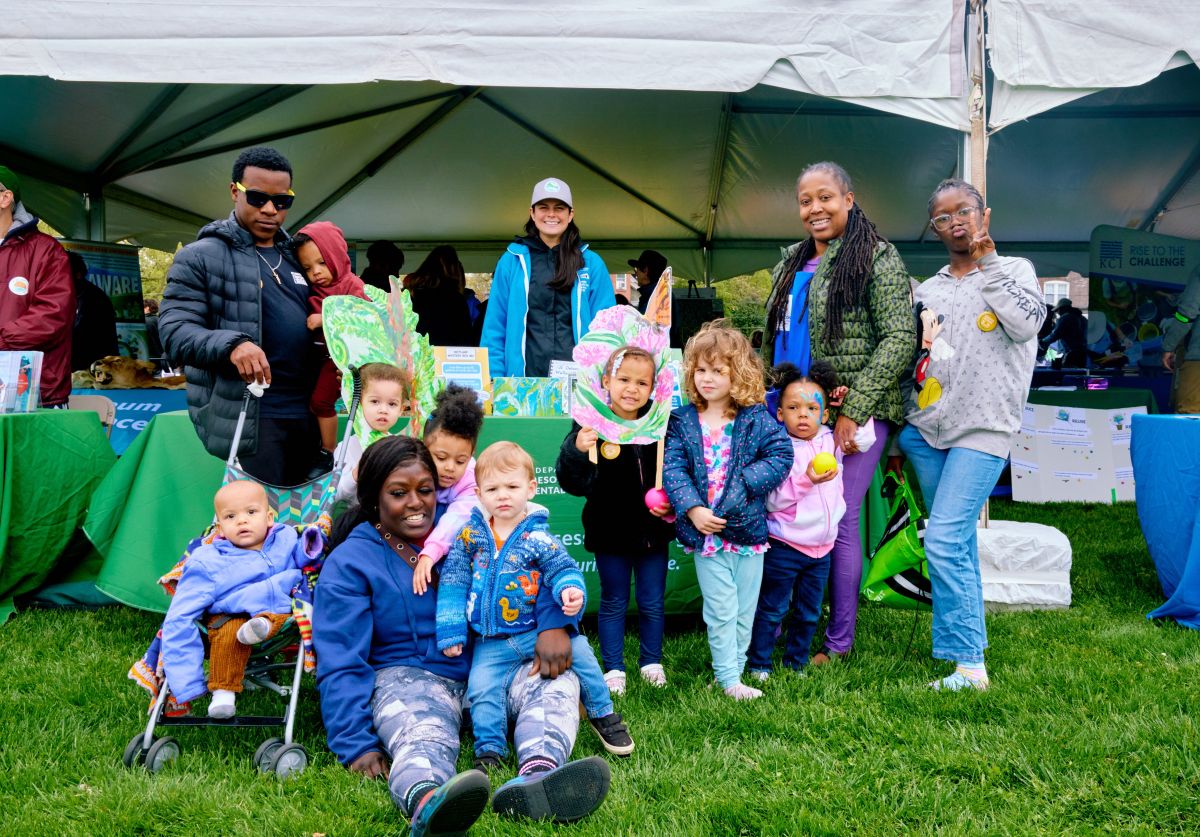 Adults and children gathered next to a text with displays.