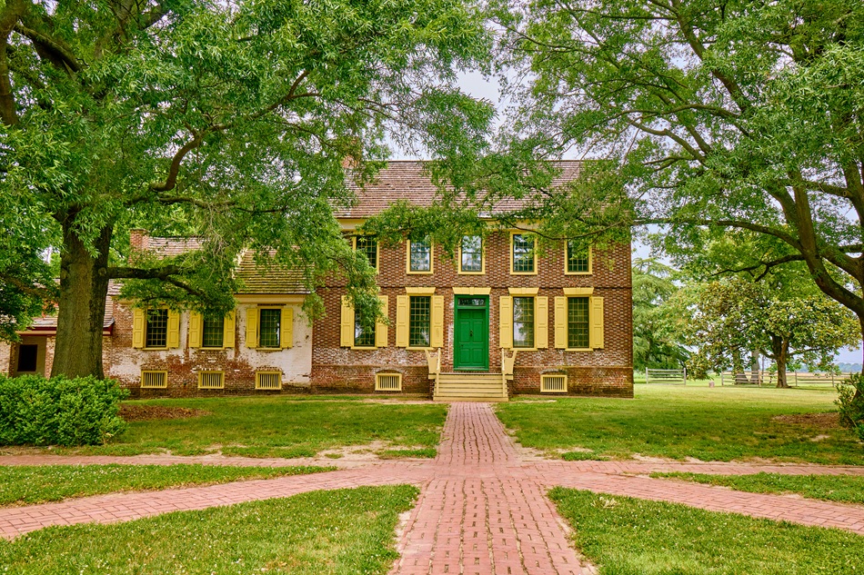 A historic brick home is flanked by trees.