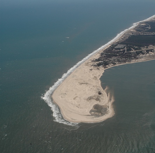 A sandy beach peninsula juts out into the water.
