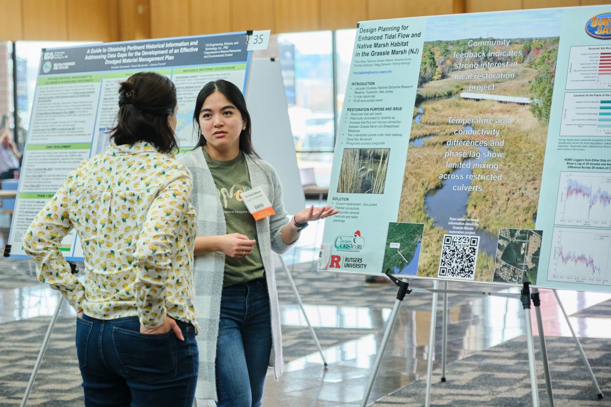 Two women discussing a poster in a conference poster session. 